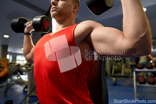 Image of close up of man with dumbbells exercising in gym