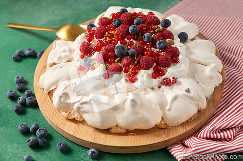 Image of pavlova meringue cake with berries on wooden board