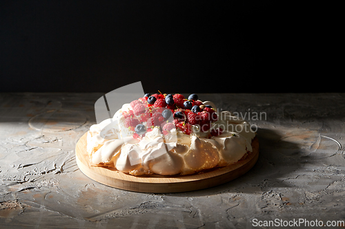 Image of pavlova meringue cake with berries on wooden board