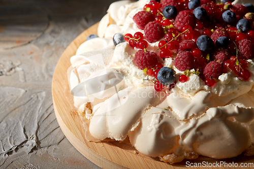 Image of pavlova meringue cake with berries on wooden board