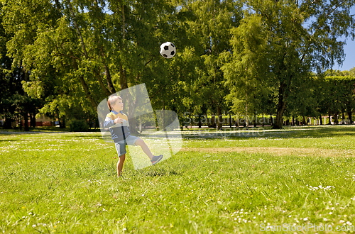 Image of happy little boy with ball playing soccer at park