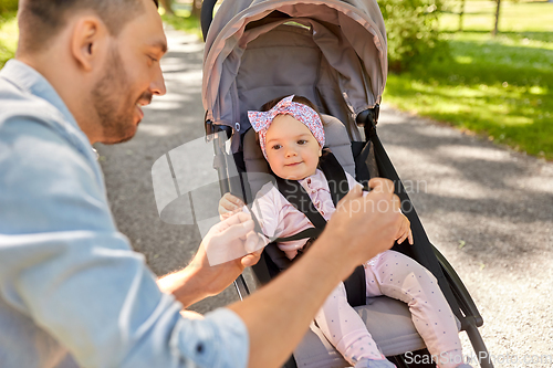 Image of happy father with child in stroller at summer park