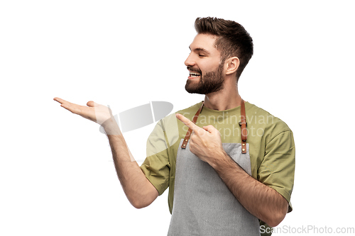 Image of happy barman in apron holding something imaginary