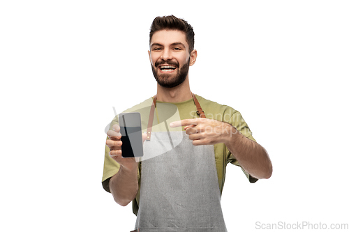 Image of happy smiling barman in apron showing smartphone