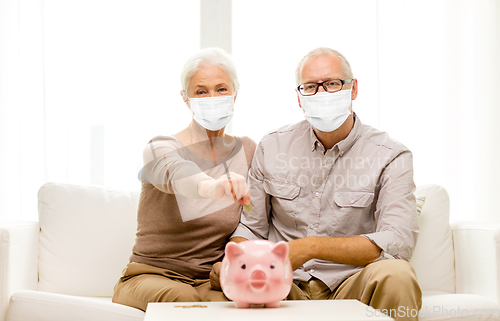 Image of old couple in masks putting coin into piggy bank