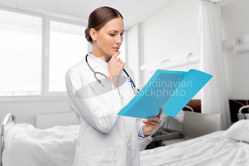 Image of thinking female doctor with folder at hospital