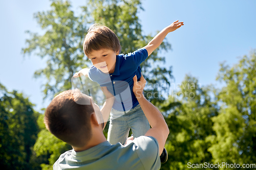 Image of happy father with son playing in summer park