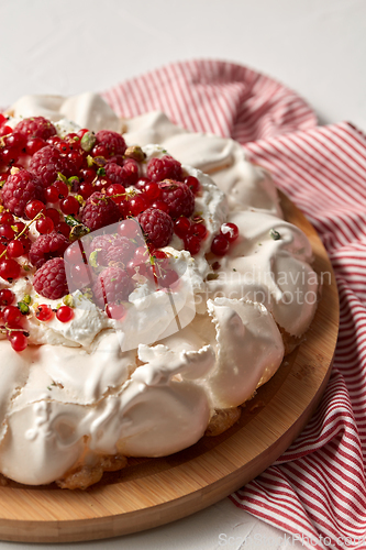 Image of pavlova meringue cake with berries on wooden board