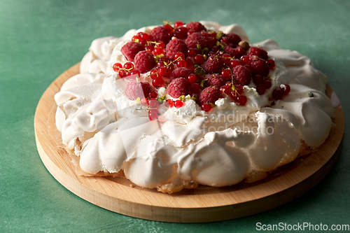 Image of pavlova meringue cake with berries on wooden board