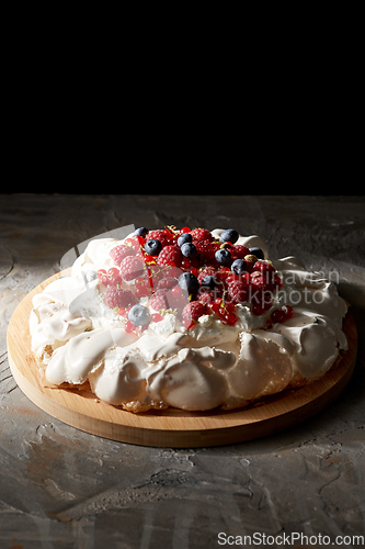 Image of pavlova meringue cake with berries on wooden board