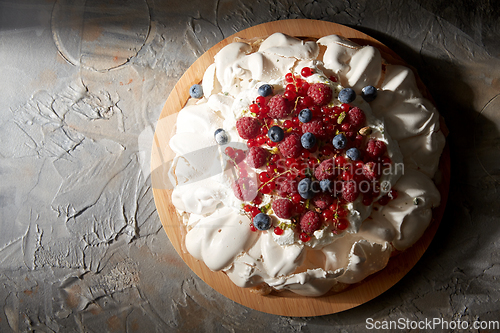 Image of pavlova meringue cake with berries on wooden board