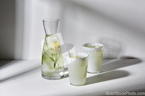 Image of glasses with lemon water and cucumber on table