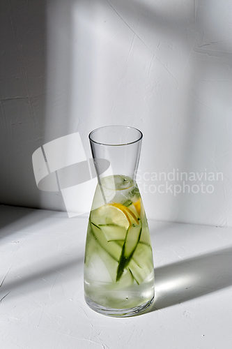 Image of glass bottle of lemon water and cucumber on table