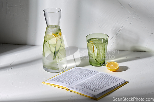 Image of glass of water with lemon and cucumber and book