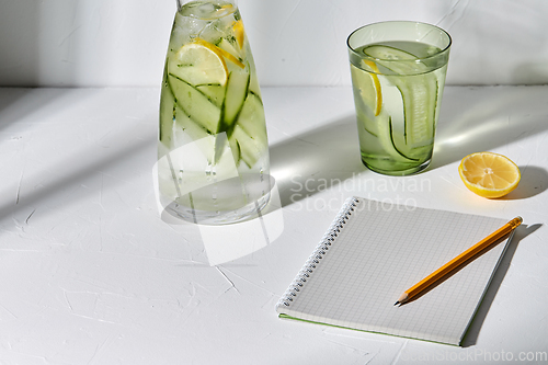 Image of water with lemon and cucumber and notebook