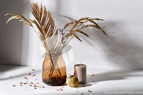 Image of dried flowers in glass vase candle and pumpkin