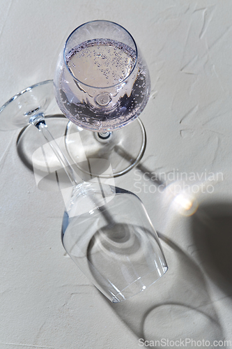 Image of wine glasses dropping shadows on white surface