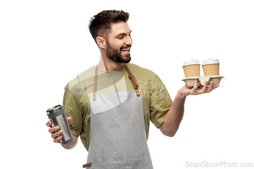 Image of happy waiter with takeout coffee cups and tumbler