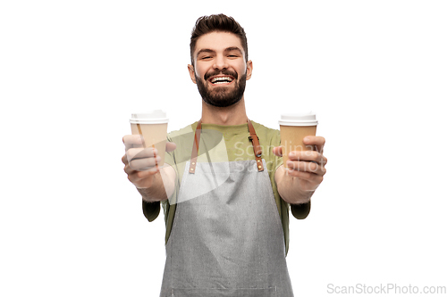 Image of happy smiling barman in apron with takeaway coffee