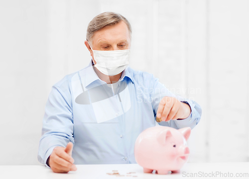 Image of old man in mask putting coin into big piggy bank