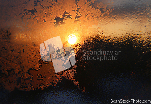 Image of Ice patterns, water drops and sunlight on a winter window glasss