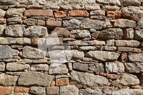 Image of Texture of an old wall of stones and bricks lit by sunlight