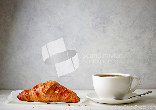 Image of freshly baked croissant and cup of coffee