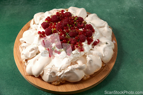 Image of pavlova meringue cake with berries on wooden board