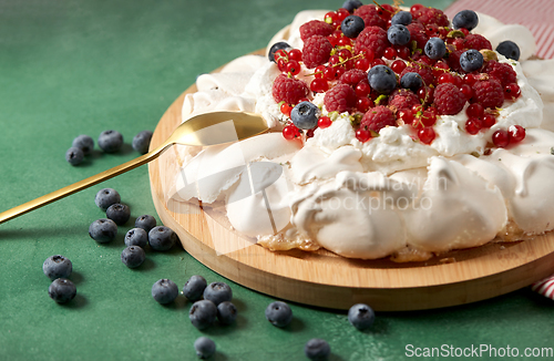 Image of pavlova meringue cake with berries on wooden board