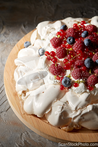 Image of pavlova meringue cake with berries on wooden board