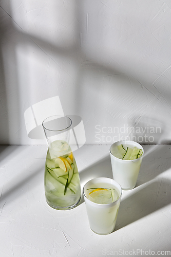 Image of glasses with lemon water and cucumber on table