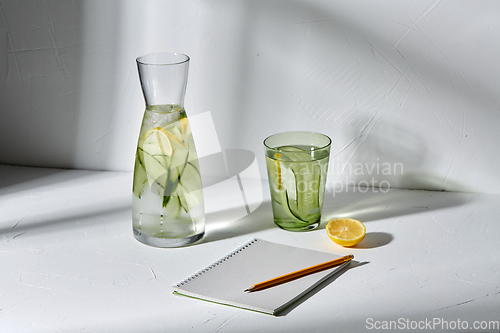 Image of water with lemon and cucumber and notebook