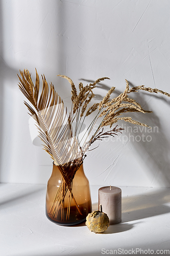 Image of dried flowers in glass vase candle and pumpkin