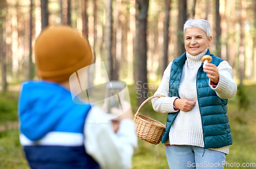 Image of grandson photographing grandmother with mushroom