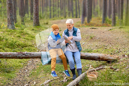 Image of grandmother with grandson drinking tea in forest