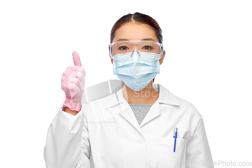 Image of asian female doctor in mask showing thumbs up