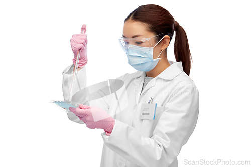 Image of asian female scientist in mask working on vaccine