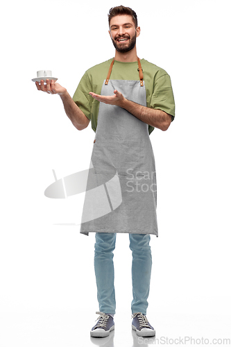 Image of happy smiling waiter in apron with cup of coffee