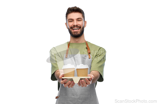 Image of happy smiling barman in apron with takeaway coffee