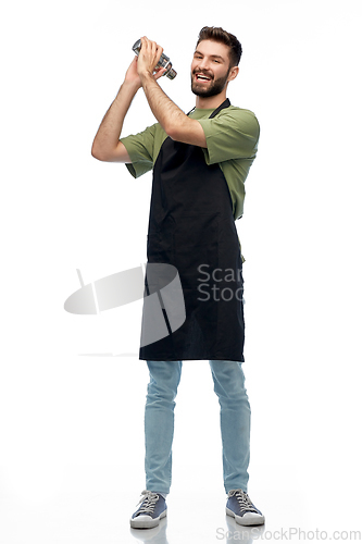 Image of happy barman in apron with shaker preparing drink