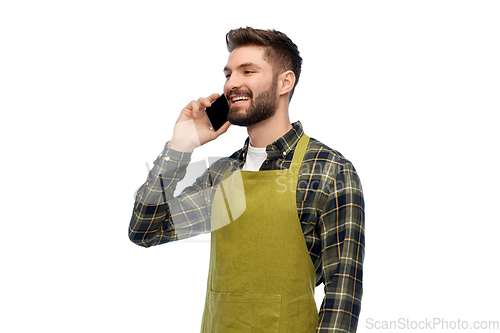Image of happy male gardener in apron calling on smartphone