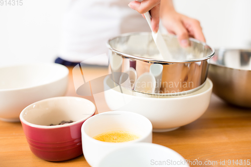 Image of Woman sifting flour through a sieve in a bowl