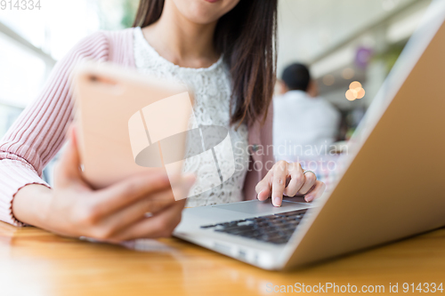 Image of Woman using laptop computer and cellphone