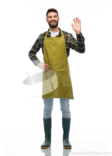 Image of happy male gardener or farmer in apron waving hand