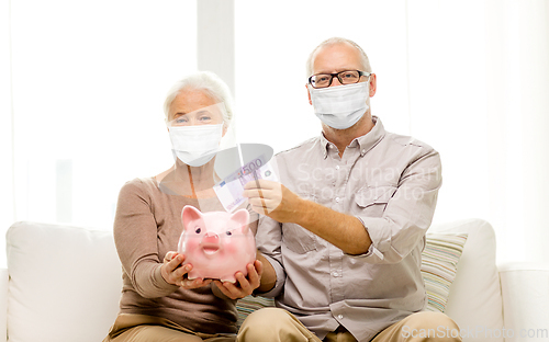 Image of old couple in masks putting money into piggy bank