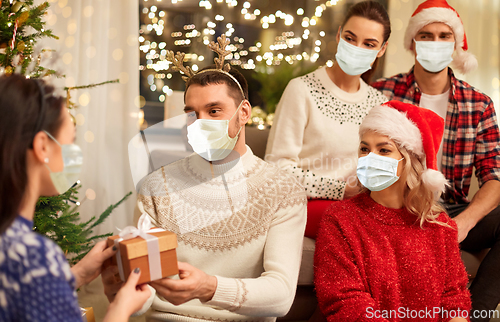 Image of friends in masks celebrating christmas at home