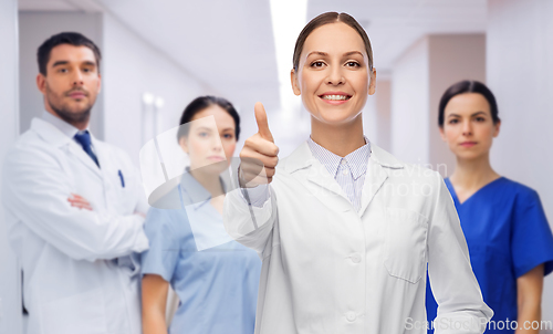 Image of doctor with colleagues shows thumbs up at hospital