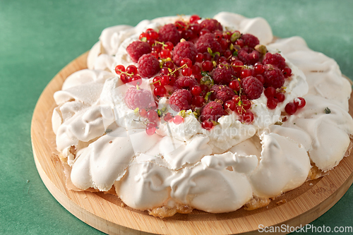 Image of pavlova meringue cake with berries on wooden board