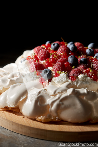 Image of pavlova meringue cake with berries on wooden board