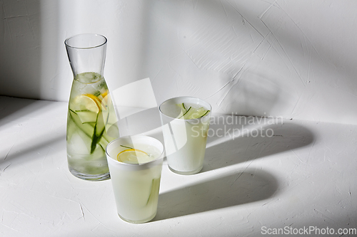 Image of glasses with lemon water and cucumber on table